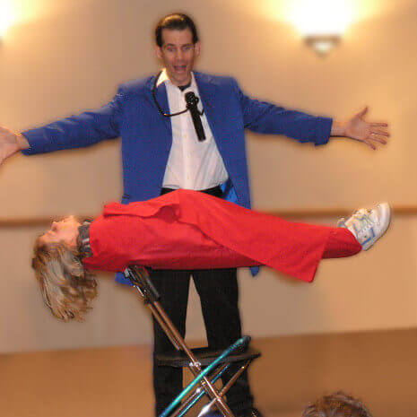 Magician performs floating girl illusion with a volunteer from the audience during Chicago area magic program!